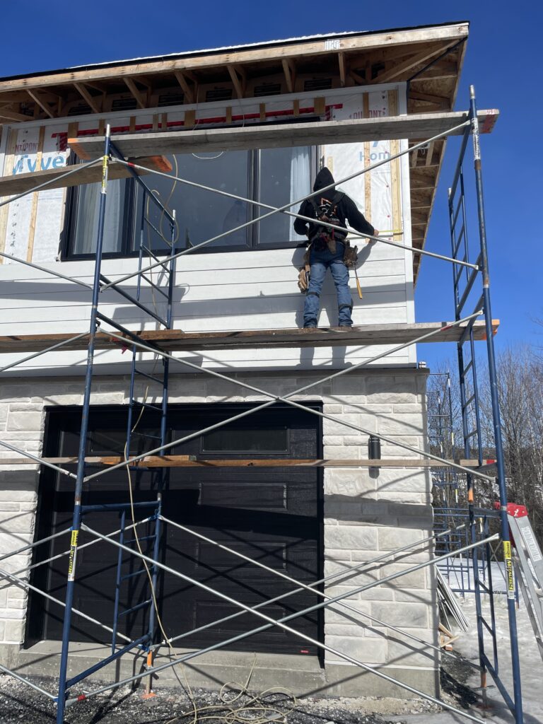 Charpentier sur échaffaux lors de la construction d'una maison neuve à Beauceville